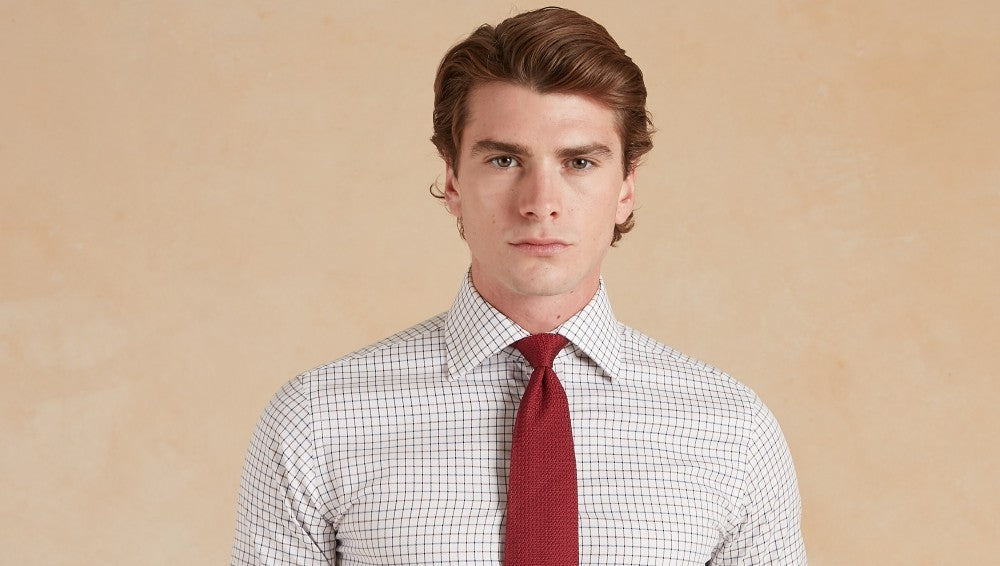 Close up of an outfit. Man wears Oliver Brown Tattersall shirt, a grouse pattern tie, a cashmere knitted waistcoat and Deveron Tweed Jacket.