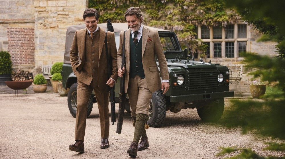 Man sitting down in country home. He wears Oliver Brown; forest green tweed jacket and twill beige trousers.