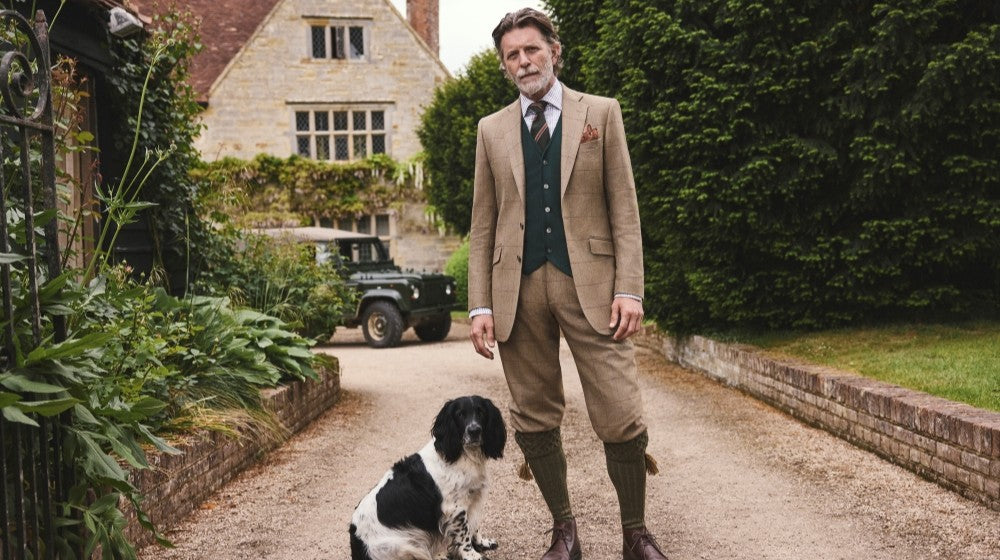 Man in the countryside wearing Oliver Brown shooting gear: breeks, shooting socks and garters, gilet and field coat all in the same limited-edition Nailhead Tweed.